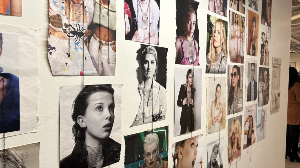 A collage of celebrity photographs, including Millie Bobby Brown, covers a wall leading into an exhibit.