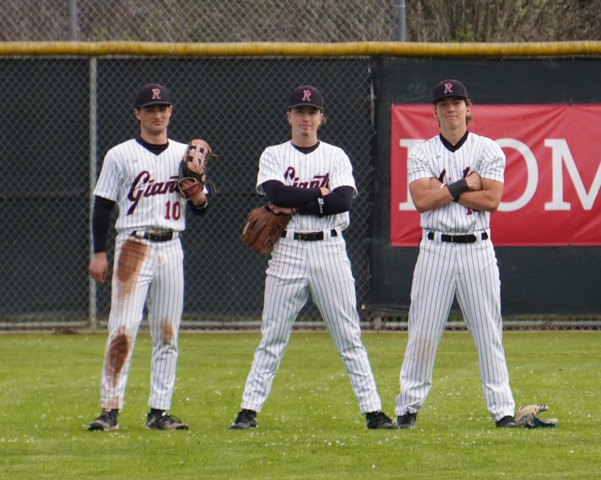 Sam Gersch, senior Gavin Soper and sophomore Jack Mosley pose for the camera in the outfield. 
