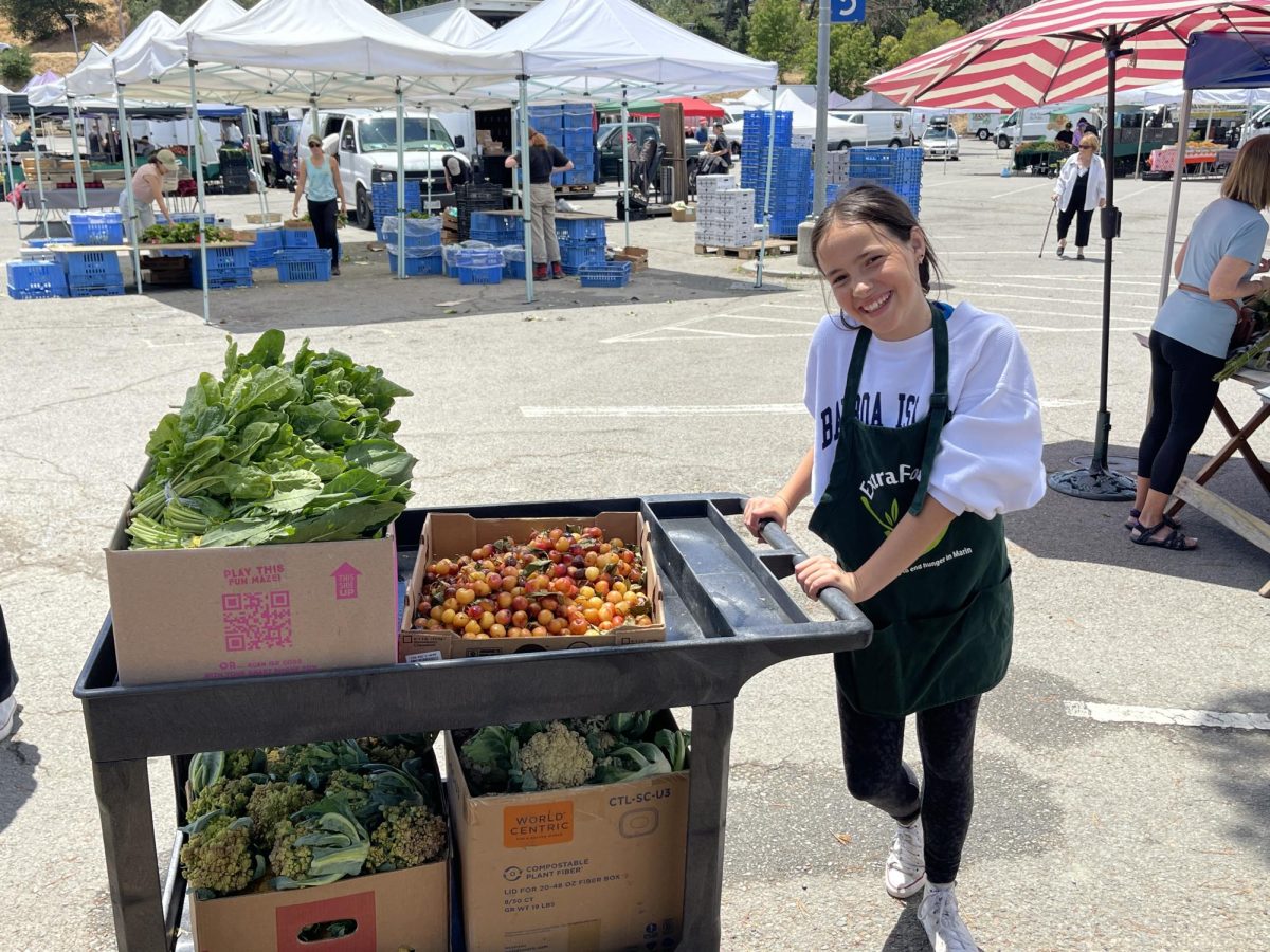 Student volunteer pushes a cart full of recovered food at the San Rafael Farmers Market to contribute to ExtraFood’s goal to end food waste (Photo courtesy of ExtraFood).
