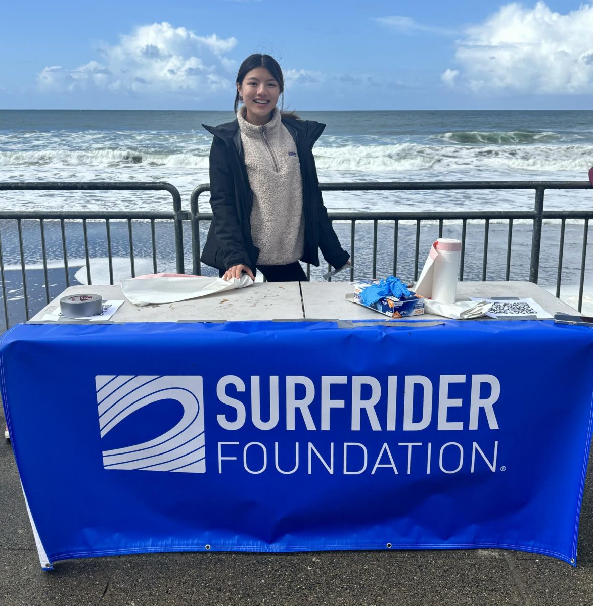 Smiling proudly, Sammy Chew poses for a picture behind the Surfrider Foundation table (Courtesy of Adriella Marcus)
