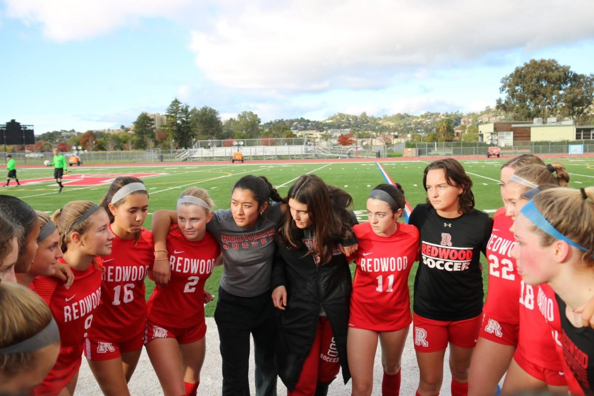 Huddling up before the game, the team gets excited for their first match and many players' varsity debut.
