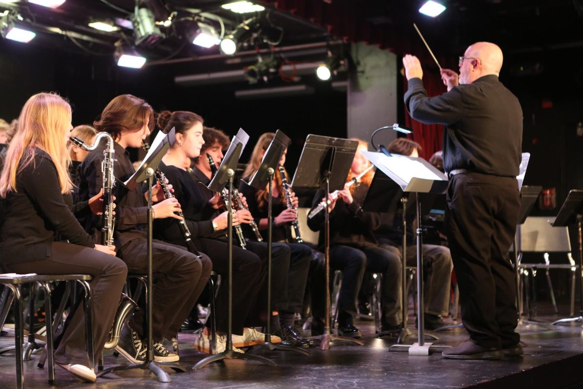 Reading their sheet music, the symphonic band flutists play in unison.  