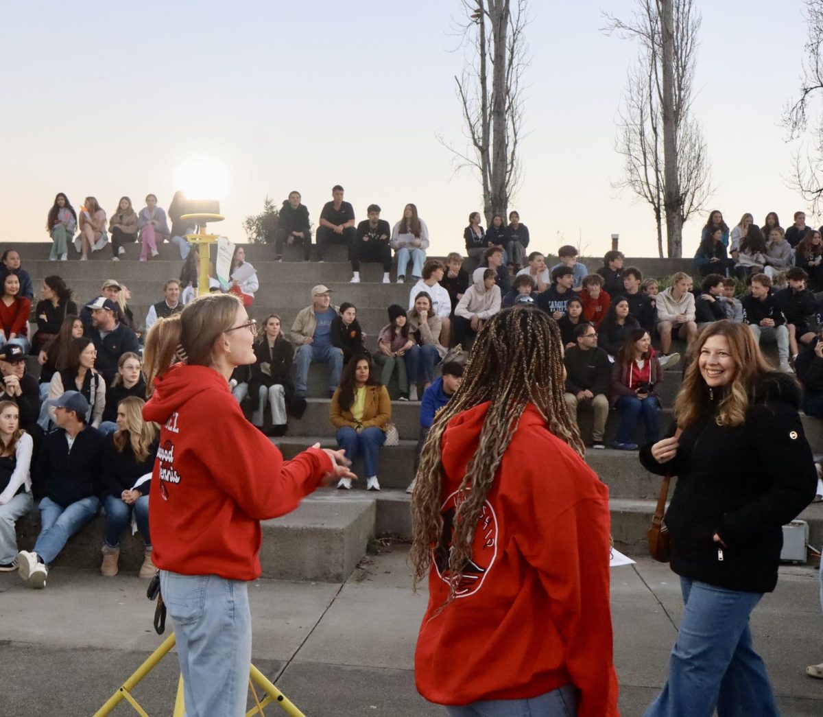 Leadership members Gwen Ricordel (senior) and Eve Dhaiti (freshman) welcome an eighth-grade parent to Redwood in front of the amphitheater.