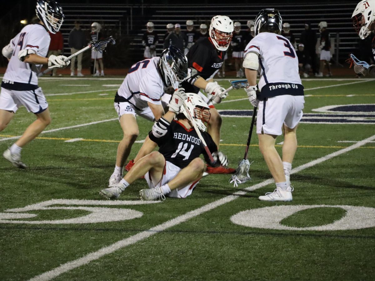 Senior John Anderluh (14) falls to the ground after putting up a hard fight to get a ground ball.
