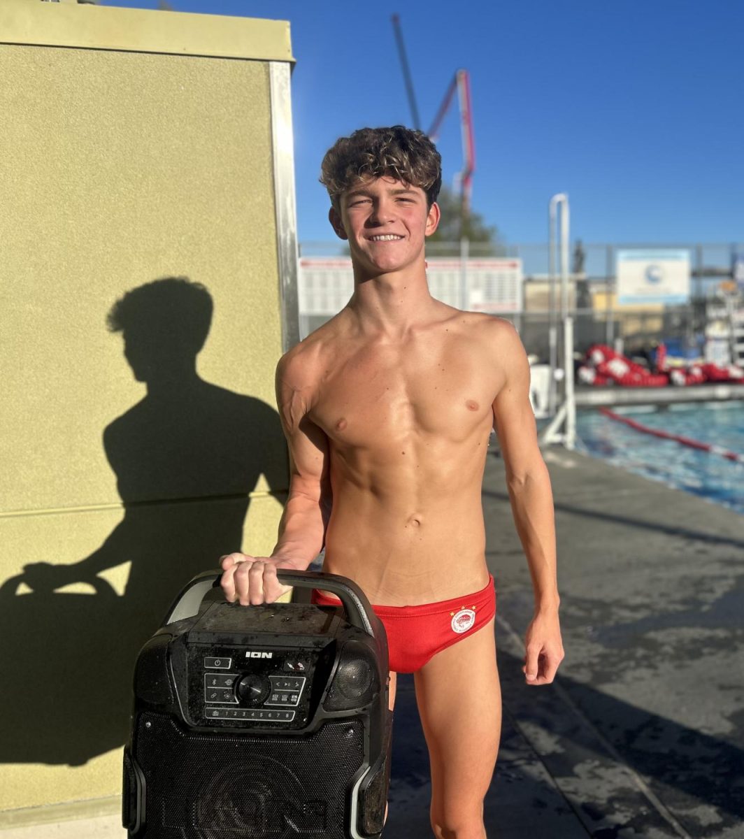 Senior Oliver Rogers moves the team speaker to the pool before water polo practice as they begin to warm up.