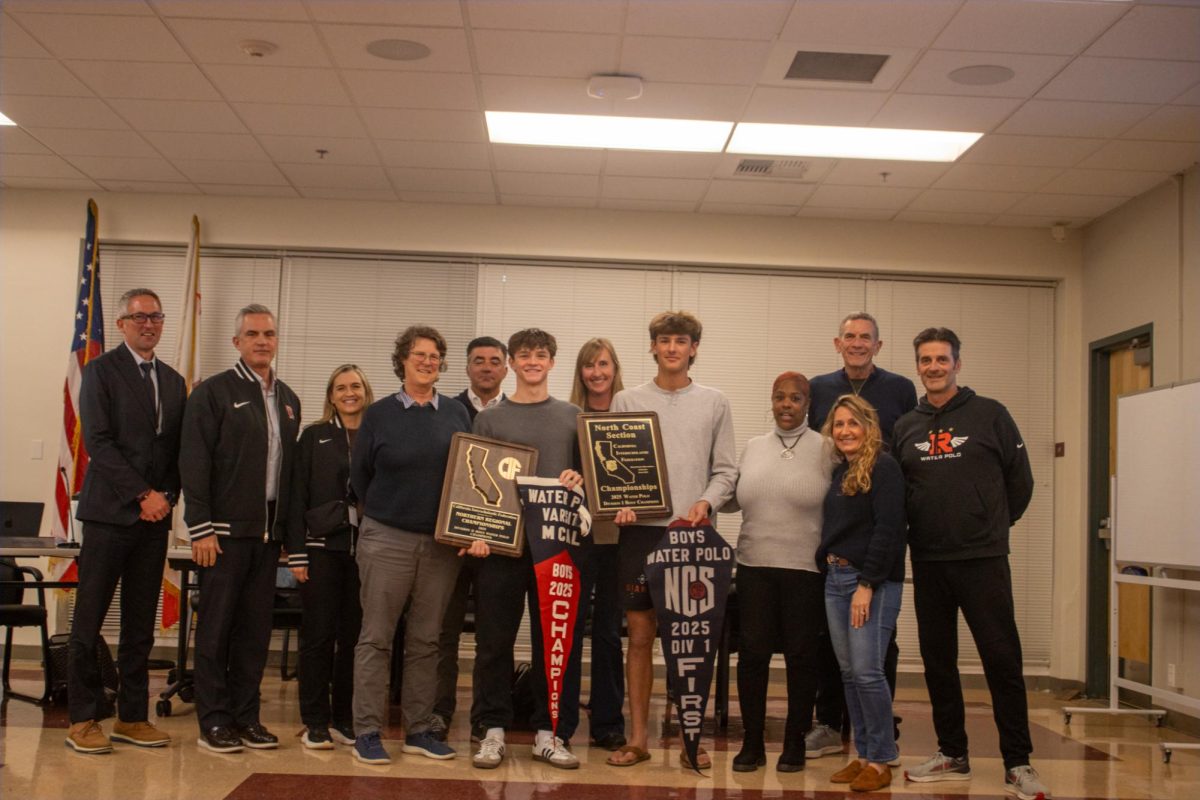 Holding up both boys’ varsity water polo North Coast Sectionals (NCS) and Norcal finals banner and plaque, sophomore Alex Marron and senior Oliver Rogers pose with board trustees and coaches.