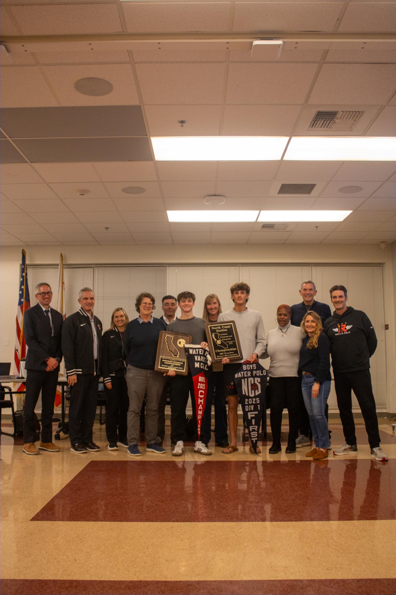 Holding up both boys’ varsity water polo North Coast Sectionals (NCS) and Norcal finals banner and plaque, sophomore Alex Marron and senior Oliver Rogers pose with board trustees and coaches.