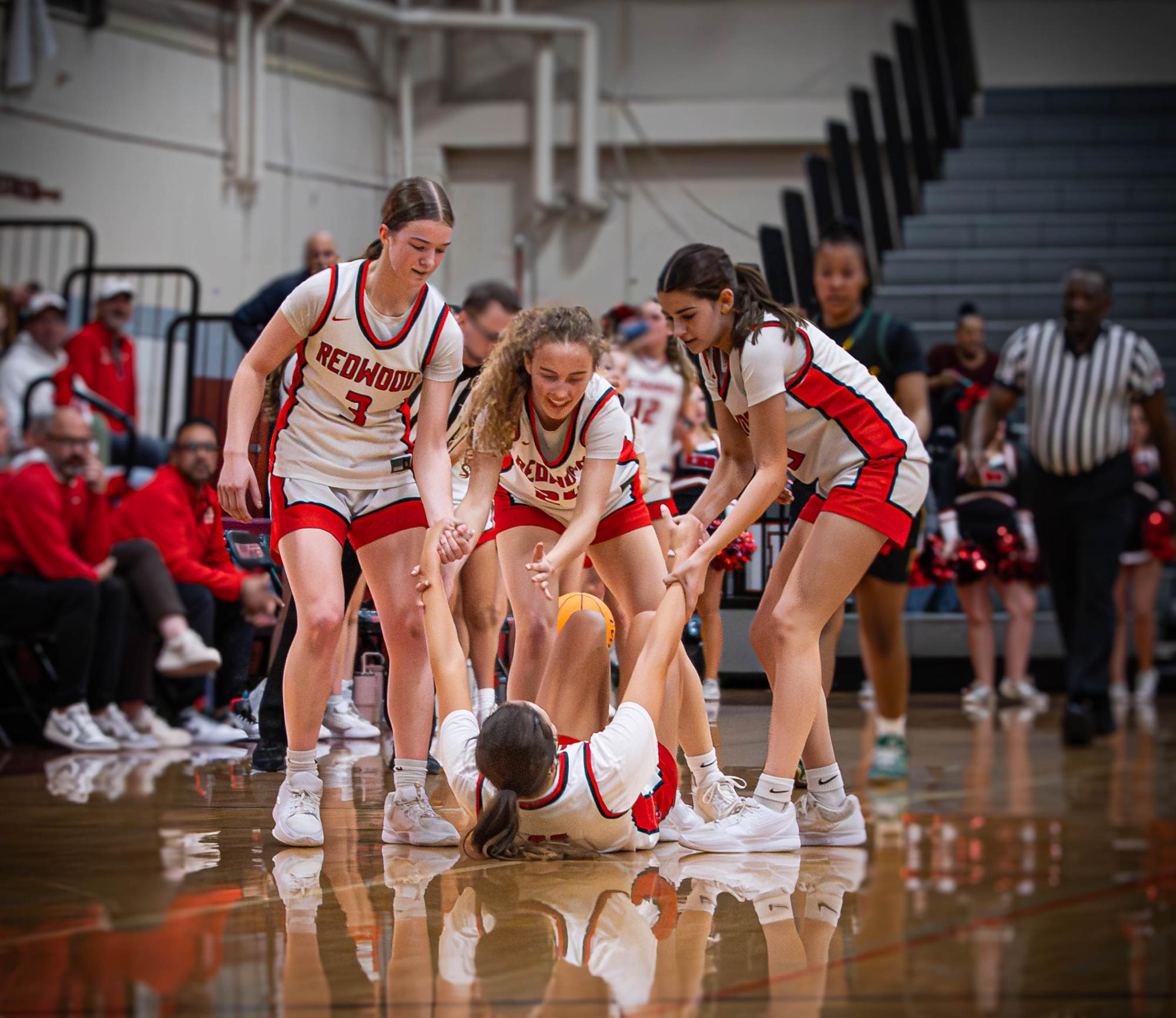 After falling to the ground, Brooke Denler’s teammates assist her back to her feet.