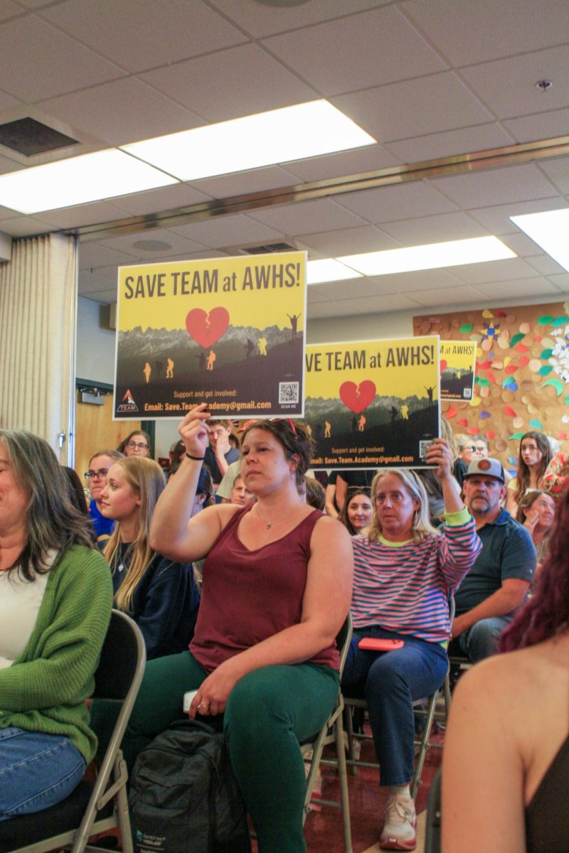 TEAM Alumni Diana Helmuth (left) holds a sign titled “SAVE TEAM at AWHS!” in protest of the recent reduction of the program.