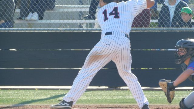 Adjusting himself to swing, junior Matthew Knauer watches the pitch.