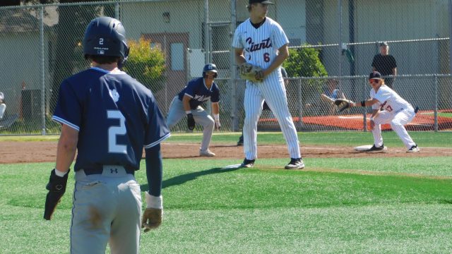 Rex Solle stares down the batter as Wildcat runners threaten at first and third base.